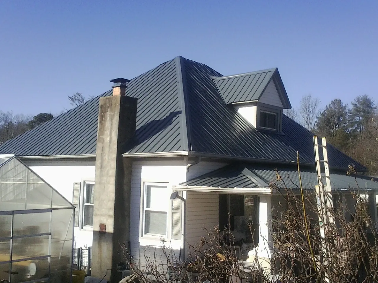 Dark blue standing seam metal roof on a white farmhouse with dormer — Slate & Tile Roof Repair by Roofing Brothers in Marlinton
