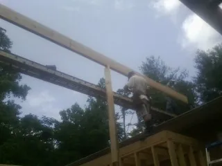 Carpenter setting a ridge beam over a new addition frame — Ice Dam Removal by Roofing Brothers in Marlinton