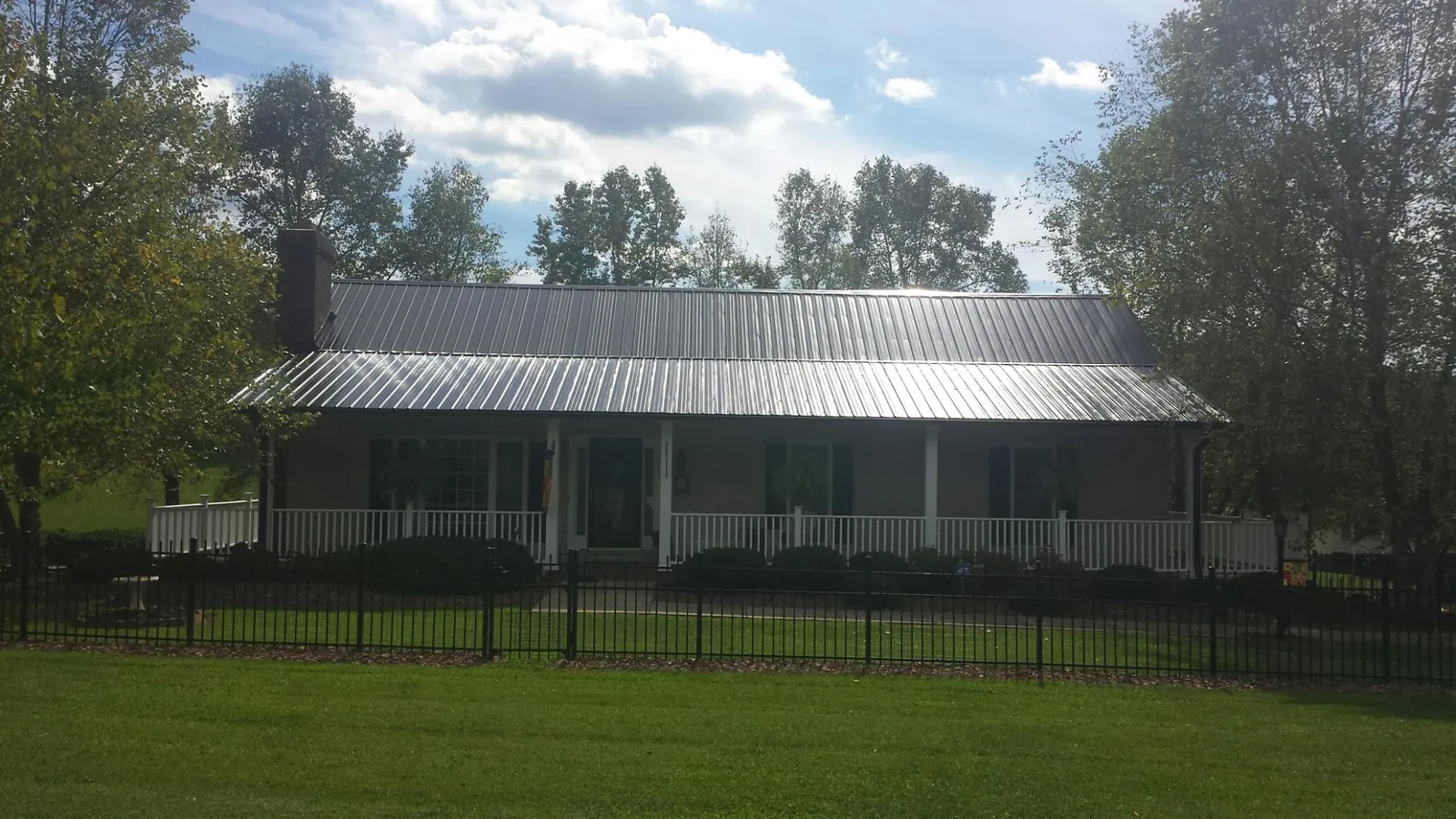 Gray metal roof on a brick ranch with a full width front porch — Gutter Guard Installation work by our crew in Marlinton