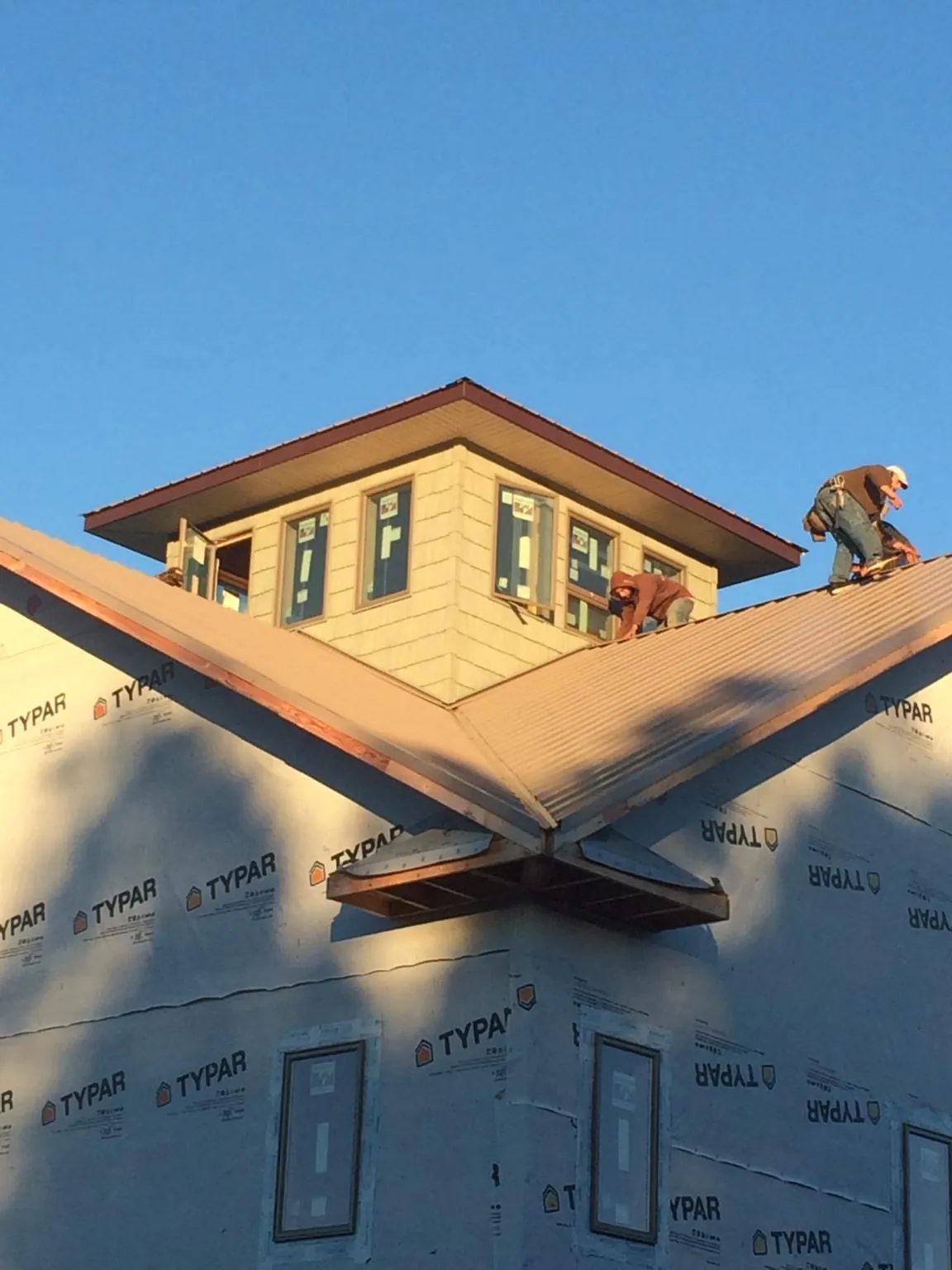 Roofers working around a rooftop cupola on a new metal roof at sunset — Roof Waterproofing in Marlinton by Roofing Brothers
